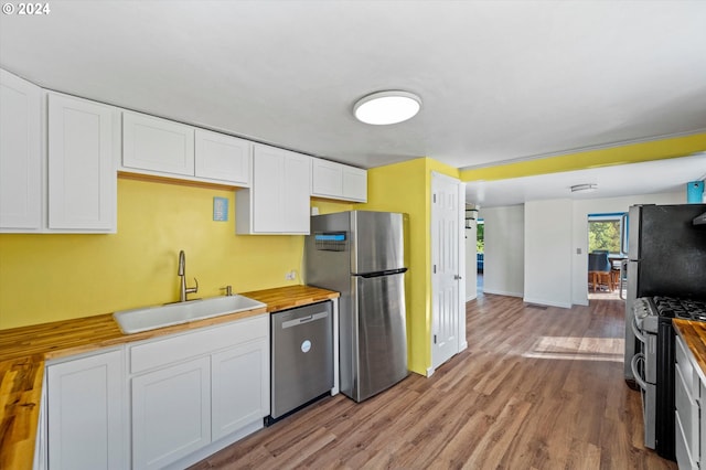 kitchen with appliances with stainless steel finishes, butcher block countertops, and white cabinets