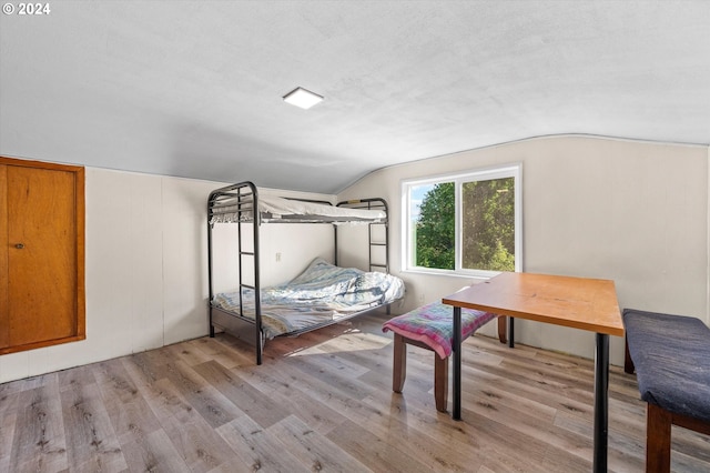 bedroom featuring a textured ceiling, lofted ceiling, and light hardwood / wood-style floors