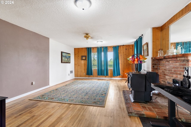 living room featuring a textured ceiling, wood-type flooring, wood walls, and a wood stove