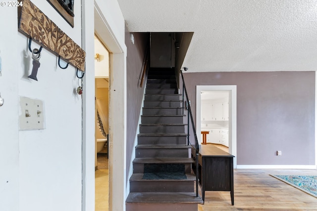 staircase featuring wood-type flooring and a textured ceiling