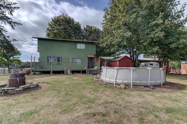 rear view of property with a yard and a swimming pool side deck