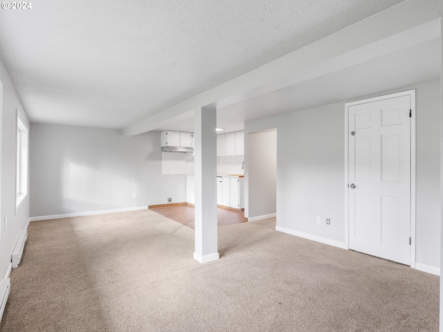 basement featuring light carpet, a textured ceiling, and a baseboard heating unit