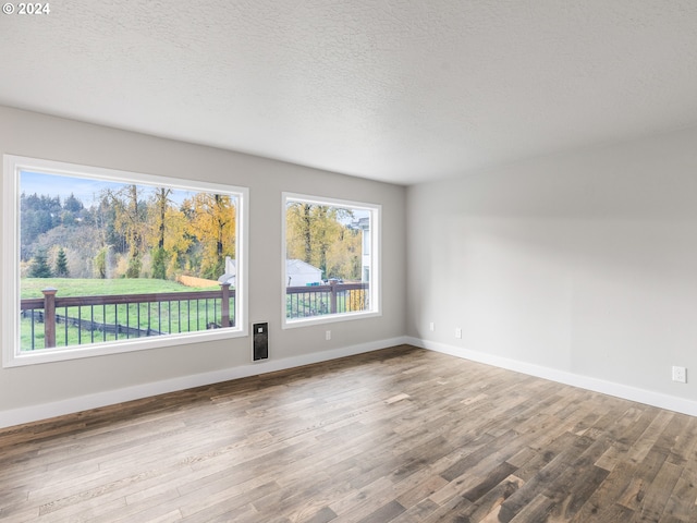 empty room with wood-type flooring and a textured ceiling