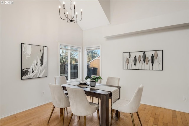 dining space with hardwood / wood-style floors, high vaulted ceiling, and a notable chandelier