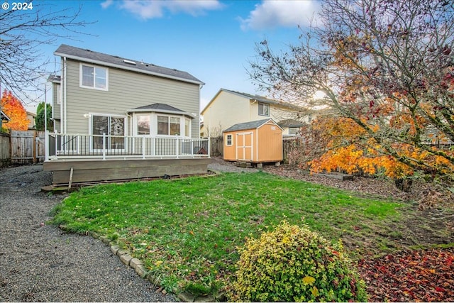 rear view of house with a wooden deck, a yard, and a storage unit