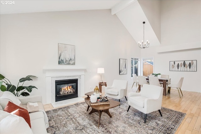 living room featuring a premium fireplace, beamed ceiling, high vaulted ceiling, a notable chandelier, and hardwood / wood-style flooring