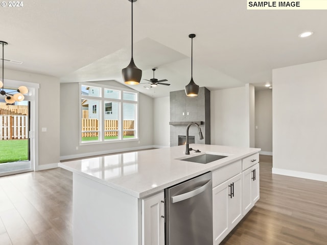 kitchen with pendant lighting, white cabinets, sink, stainless steel dishwasher, and hardwood / wood-style flooring