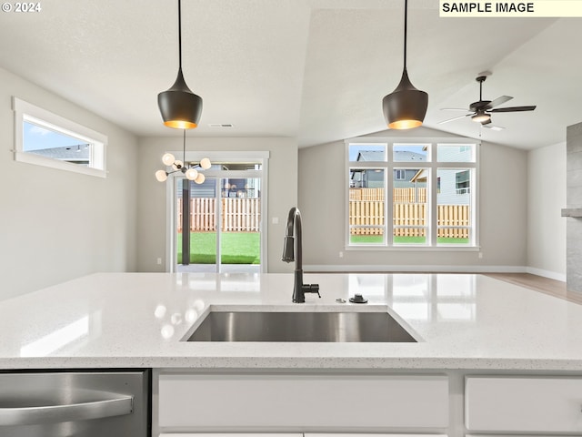 kitchen featuring light stone countertops, white cabinets, hanging light fixtures, and sink