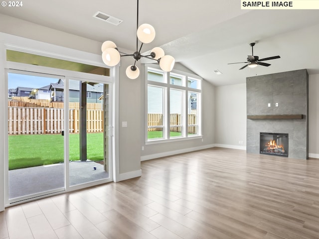 unfurnished living room featuring ceiling fan, a large fireplace, lofted ceiling, and light hardwood / wood-style flooring