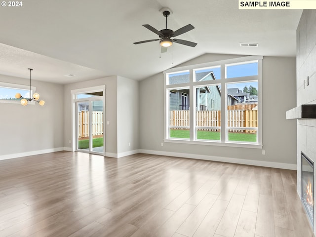 unfurnished living room featuring lofted ceiling, light hardwood / wood-style floors, a healthy amount of sunlight, and a tiled fireplace