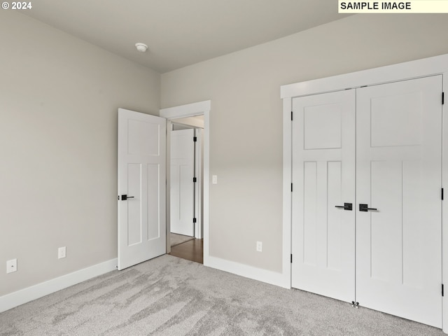 unfurnished bedroom with light carpet and a closet