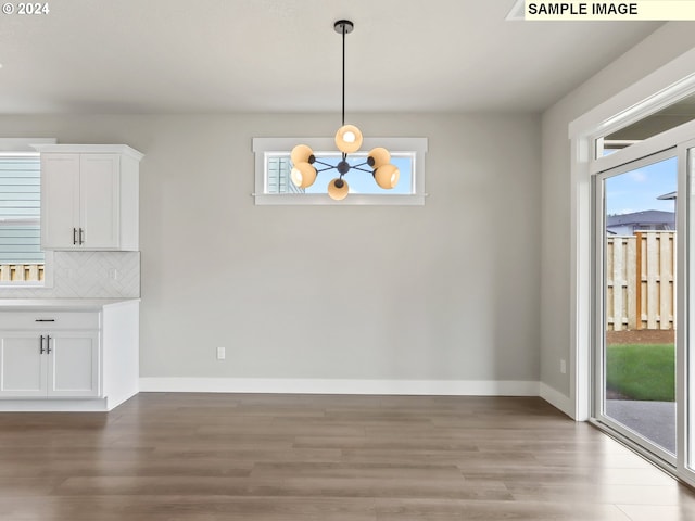 unfurnished dining area featuring wood-type flooring and an inviting chandelier