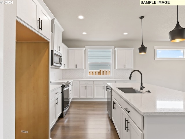 kitchen featuring hanging light fixtures, light stone countertops, sink, and appliances with stainless steel finishes