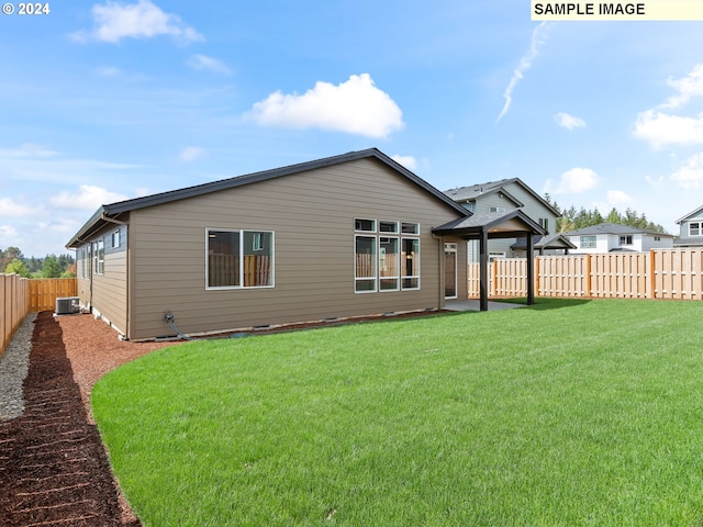 back of house with central AC unit and a yard