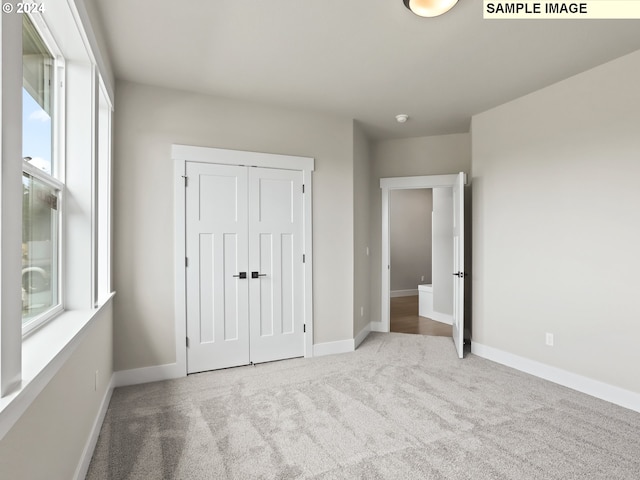 unfurnished bedroom with a closet, light colored carpet, and multiple windows