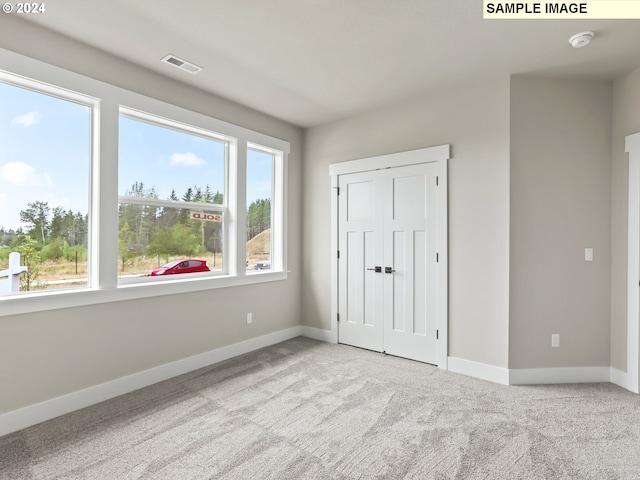 unfurnished bedroom featuring a closet, light carpet, and multiple windows