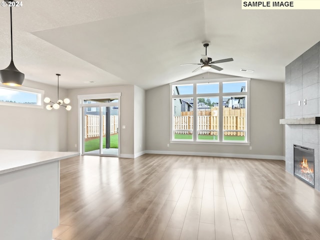 unfurnished living room with a fireplace, ceiling fan with notable chandelier, light hardwood / wood-style floors, and lofted ceiling