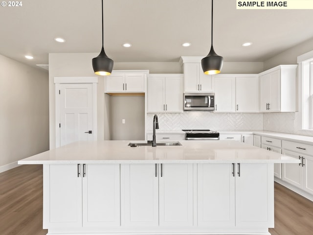 kitchen featuring pendant lighting, an island with sink, stainless steel appliances, and sink