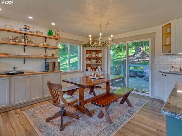 dining area featuring light hardwood / wood-style flooring, a chandelier, and a textured ceiling