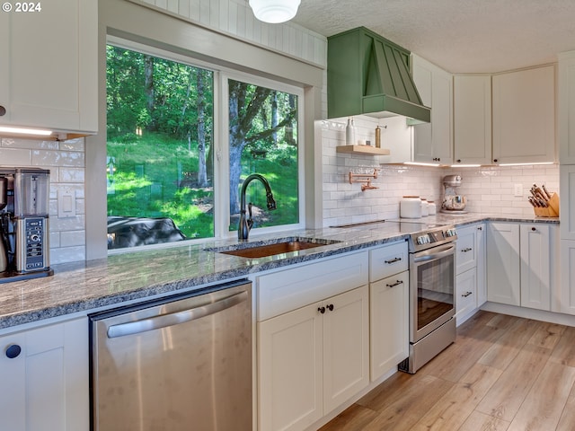 kitchen featuring white cabinets, sink, light hardwood / wood-style flooring, light stone countertops, and stainless steel appliances