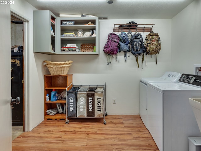 laundry room with separate washer and dryer, light hardwood / wood-style flooring, and a textured ceiling