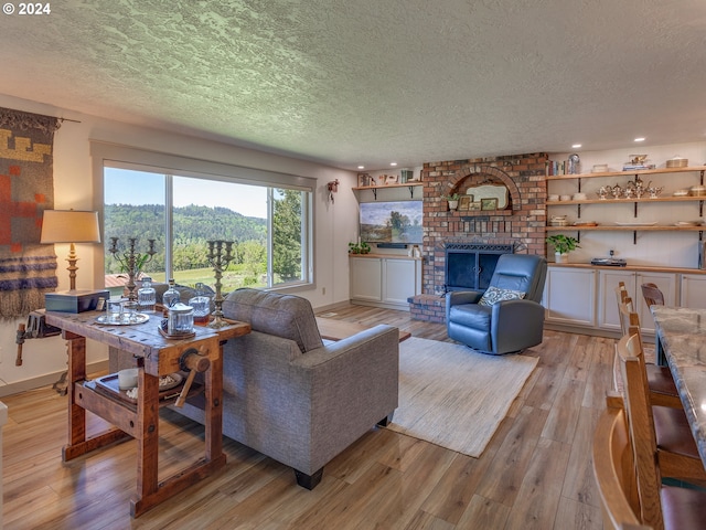 living room with a fireplace, light wood-type flooring, and a textured ceiling