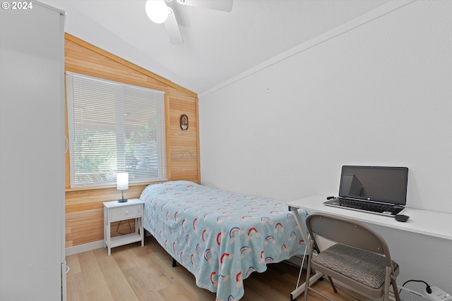 bedroom featuring lofted ceiling, ceiling fan, wooden walls, and wood finished floors