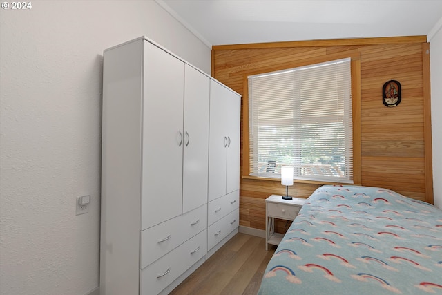 bedroom featuring a closet, wooden walls, and light wood finished floors