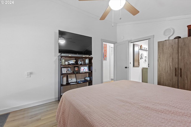 bedroom with light wood-style floors, vaulted ceiling, crown molding, and a ceiling fan