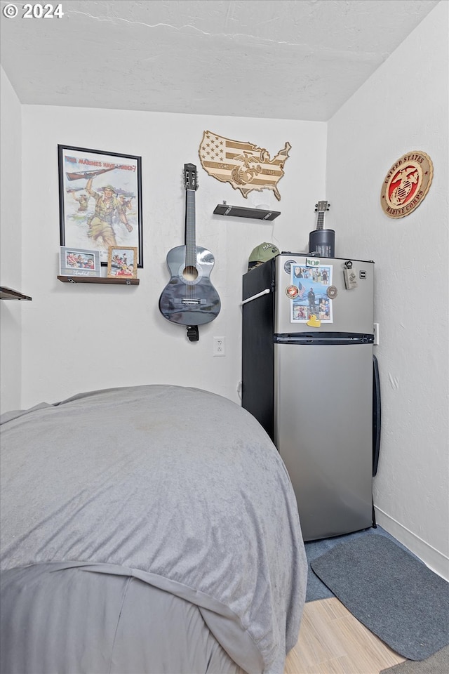 bedroom featuring freestanding refrigerator, baseboards, and wood finished floors