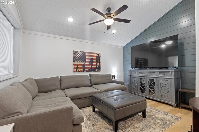 living room with vaulted ceiling, wooden walls, wood ceiling, ceiling fan, and light wood-type flooring