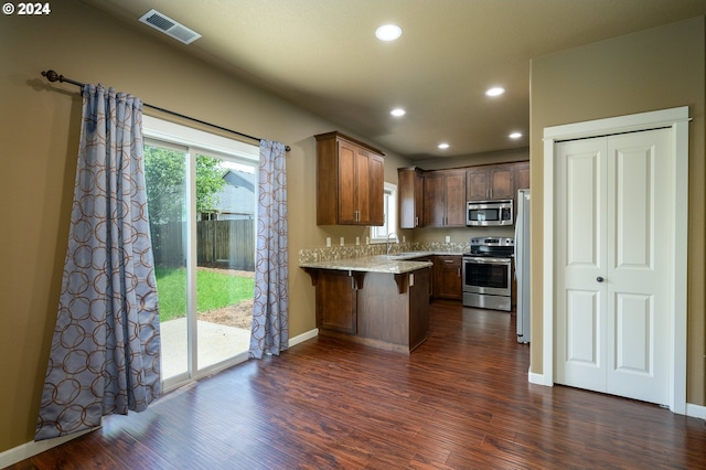 kitchen with dark hardwood / wood-style floors, stainless steel appliances, a breakfast bar, and sink