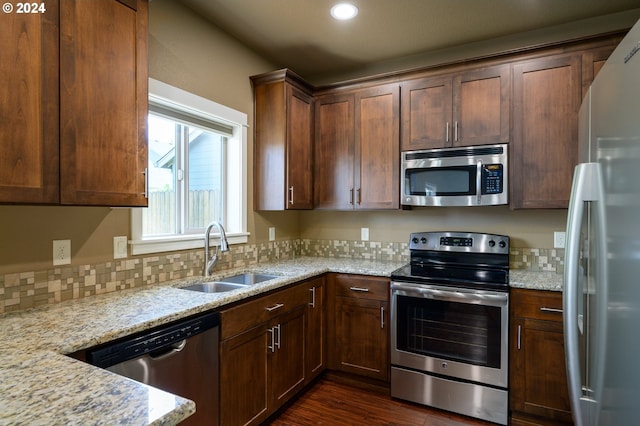 kitchen featuring light stone counters, appliances with stainless steel finishes, sink, and dark hardwood / wood-style floors