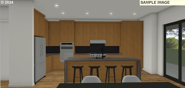 kitchen featuring a kitchen bar, sink, a center island, white appliances, and light hardwood / wood-style floors