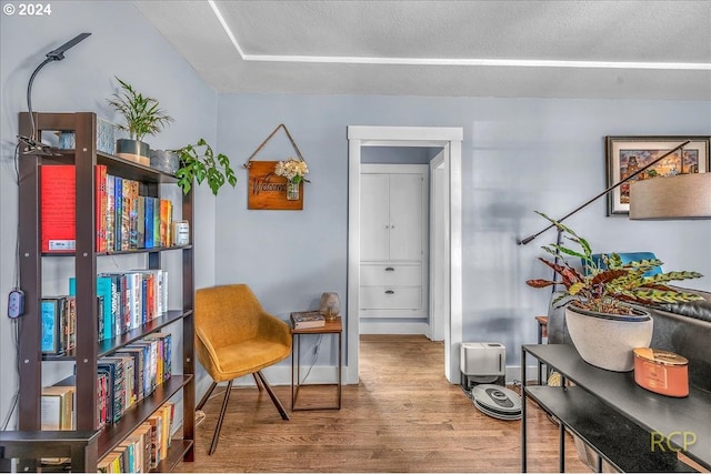 living area with wood-type flooring and a textured ceiling