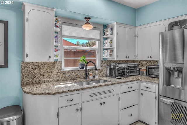 kitchen with stainless steel refrigerator with ice dispenser, backsplash, sink, and white cabinets