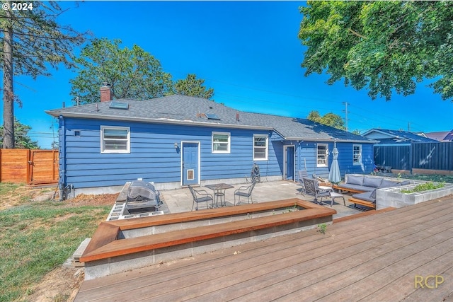 back of house featuring a wooden deck, an outdoor hangout area, and a patio area