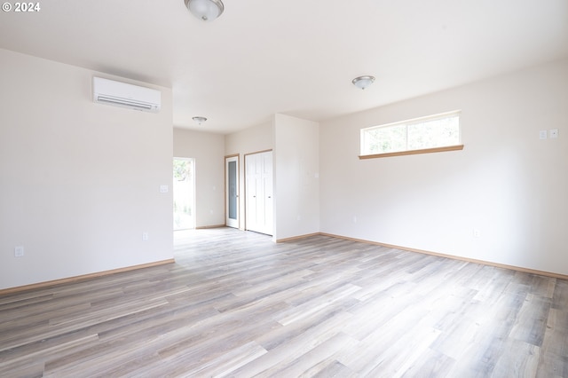 empty room featuring light wood-type flooring and a wall mounted air conditioner