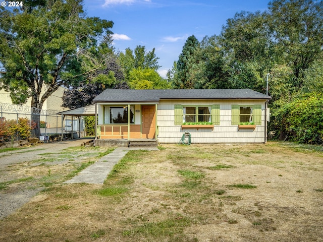 view of front of house featuring covered porch, a front yard, and fence