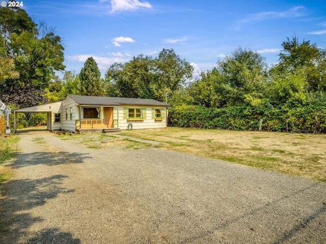 ranch-style home featuring a front lawn, a carport, and a porch