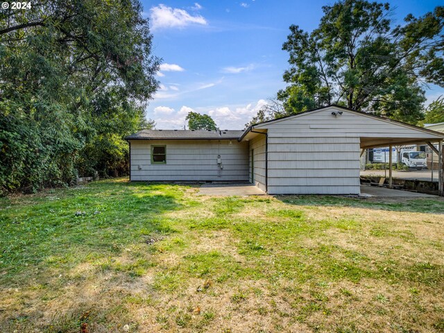 rear view of property with a yard and a carport