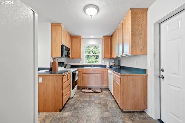 kitchen with a textured ceiling, sink, and white appliances