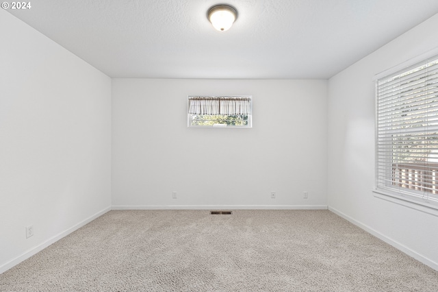 carpeted empty room featuring a textured ceiling