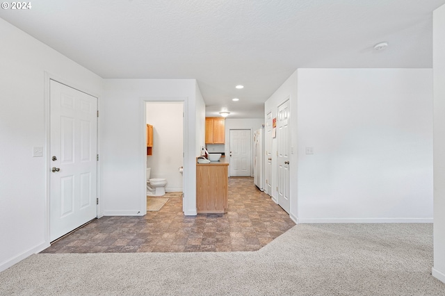 kitchen featuring light brown cabinetry, white fridge, and dark carpet