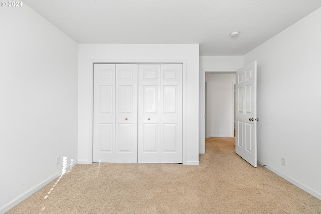 unfurnished bedroom with light carpet and a closet