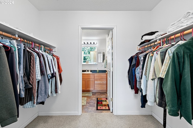 walk in closet with light carpet and sink