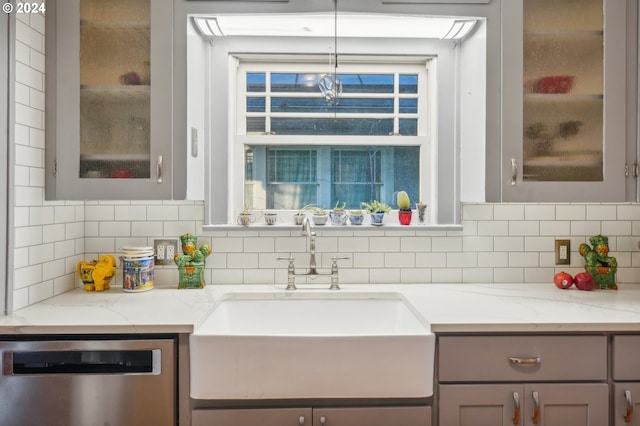 kitchen with stainless steel dishwasher, decorative backsplash, light stone countertops, and sink