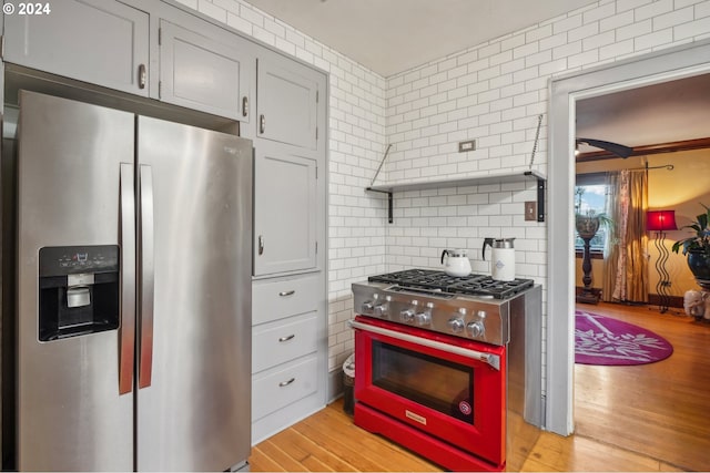 kitchen with gray cabinets, ornamental molding, tile walls, light hardwood / wood-style floors, and stainless steel appliances