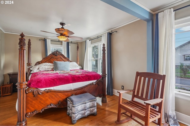 bedroom featuring ceiling fan, wood-type flooring, crown molding, and multiple windows