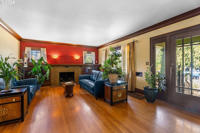 living room with wood-type flooring, a brick fireplace, a wealth of natural light, and ornamental molding